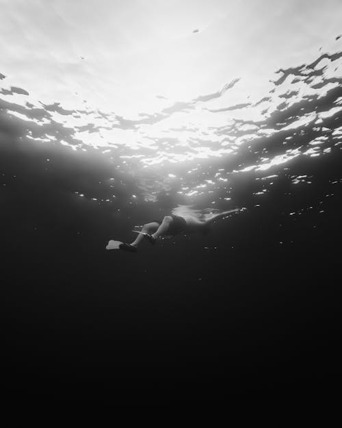 Man with Fins Swimming Near the Ocean Surface Seen from Underwater