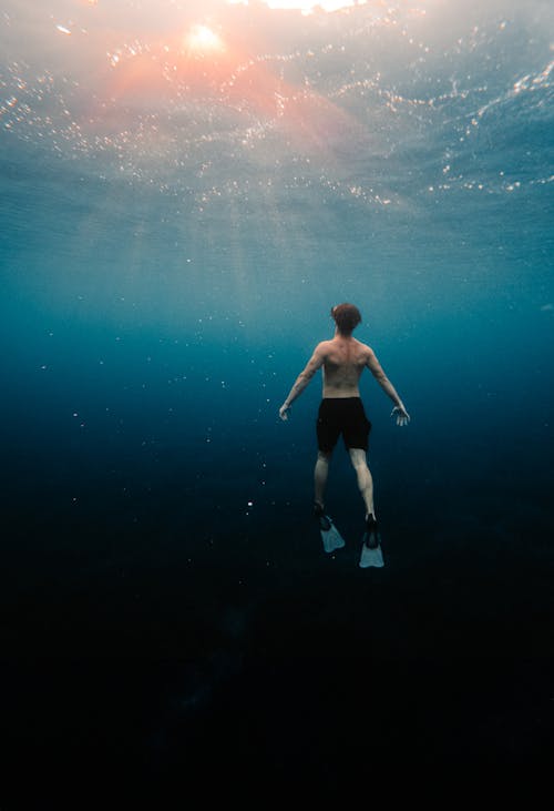 Man Underwater Looking at the Sun
