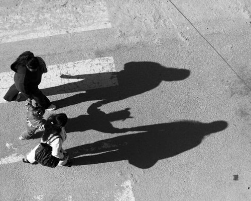 Free Black and white photo of a family crossing the street in Nepal, showing their shadows. Stock Photo