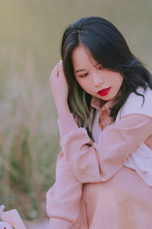 Free A thoughtful woman in a beige dress sitting outdoors in harmony with nature. Stock Photo