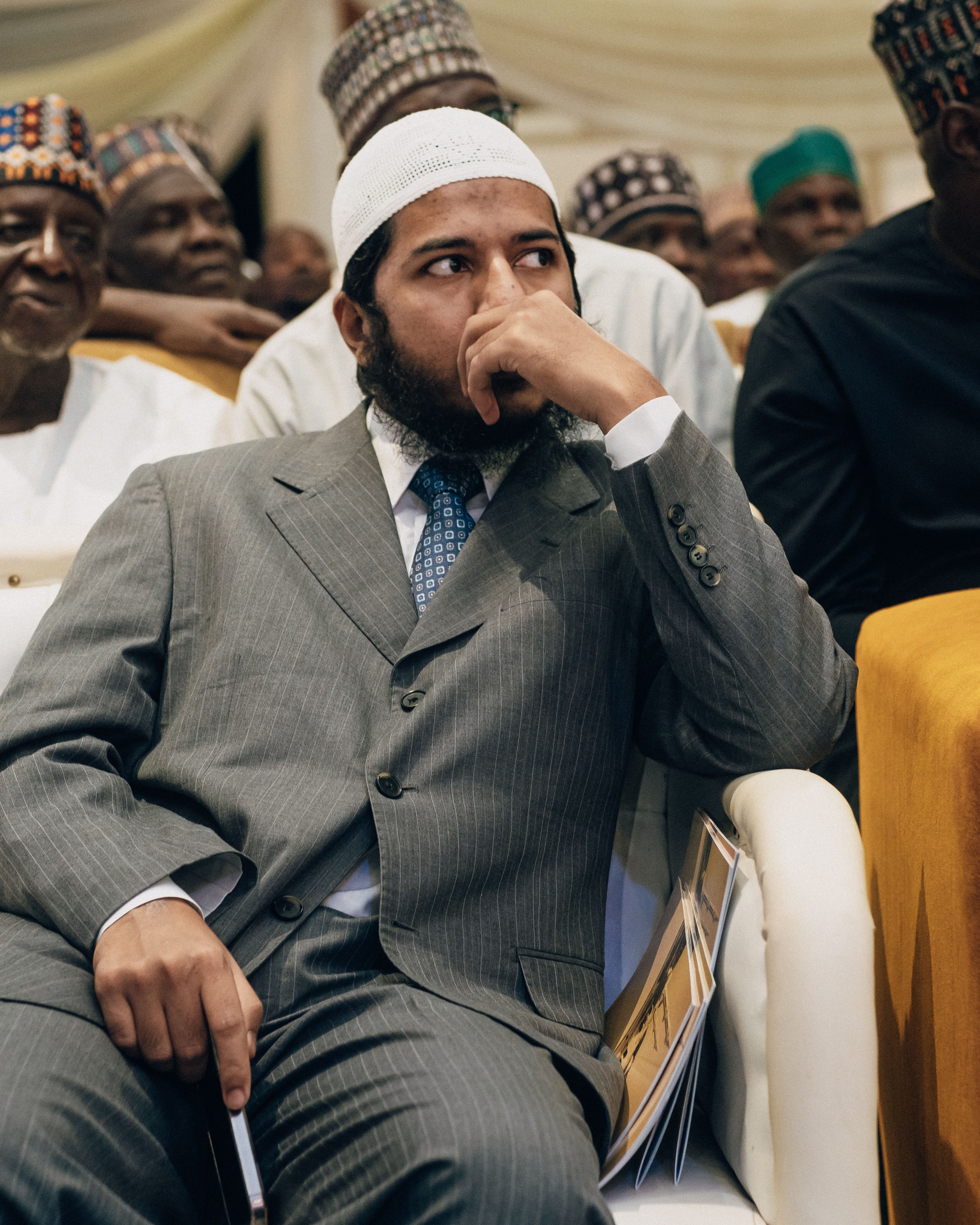 A Middle Eastern man in a suit attending a formal meeting, sitting attentively.