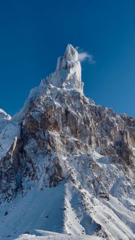 A stunning vertical shot of a snowcapped mountain towering into a clear blue sky.