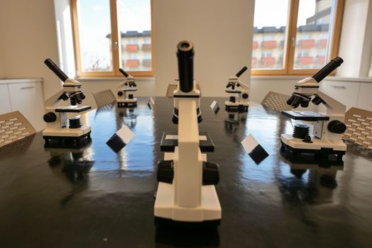 A classroom with microscopes on a black table, ready for scientific study., free online jigsaw puzzle on JigsawPuzzlesFreeOnline.org