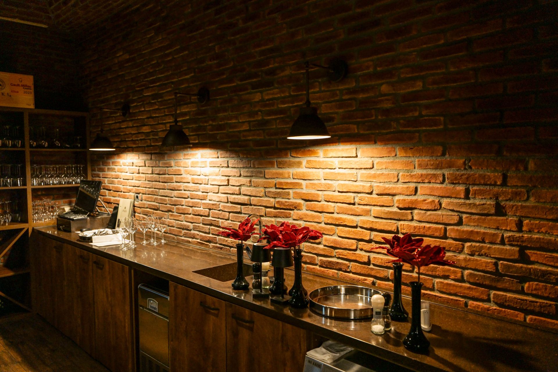 Spacious kitchen with red brick walls and soft lighting, featuring countertops and kitchenware.