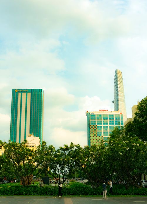 Free Skyline view of Ho Chi Minh City featuring modern architecture and lush greenery under a summer sky. Stock Photo