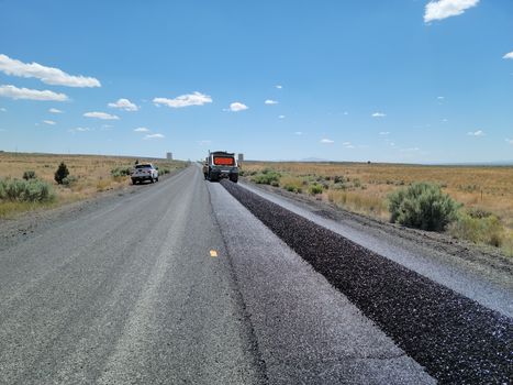 Photo by Tom Shamberger Construction equipment resurfacing a rural highway under a clear blue sky.