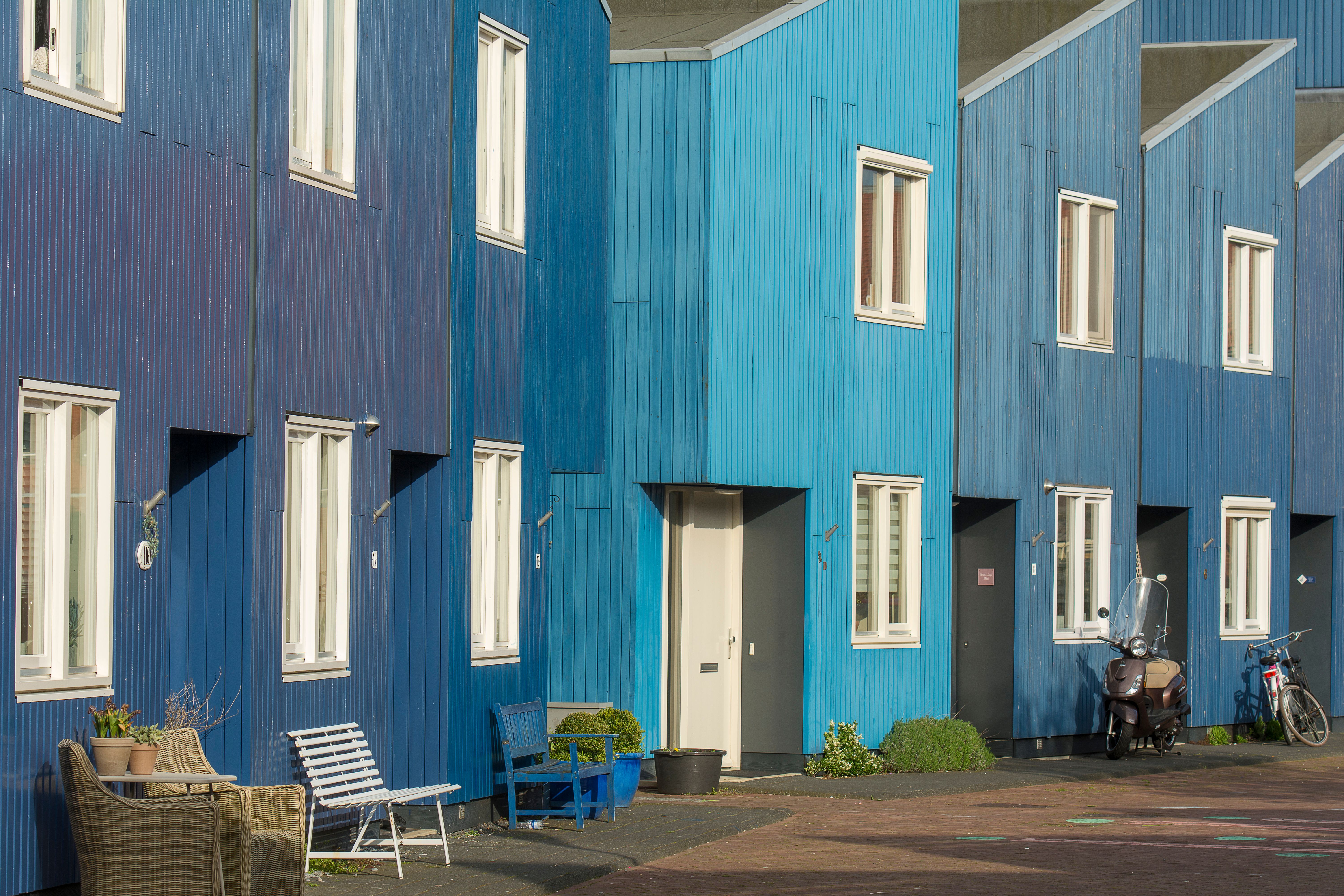 Fachada de prédios residenciais com acabamento em madeira pintada de azul, incluindo janelas e áreas de circulação externa.