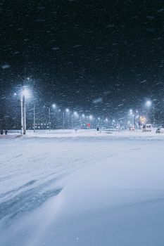 A tranquil winter night with heavy snowfall on a lit street in Vitebsk, Belarus.