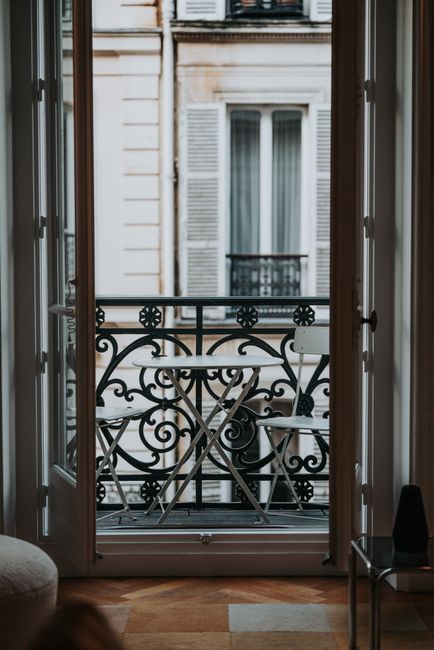 Elegant Parisian balcony featuring intricate ironwork and a cozy seating arrangement. Perfect for urban lifestyle imagery.