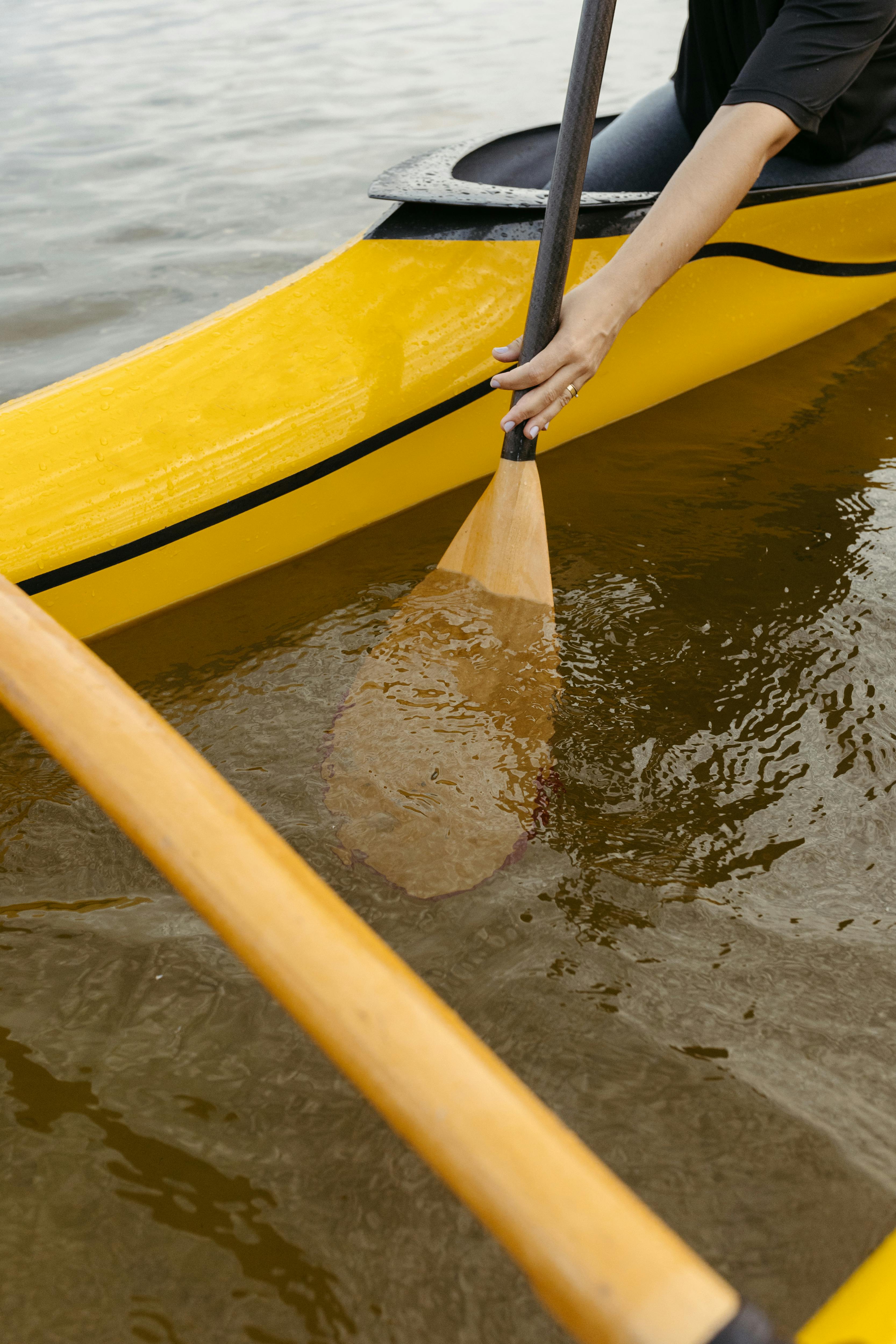 A woman paddles a yellow canoe on calm water, highlighting leisure and recreation.