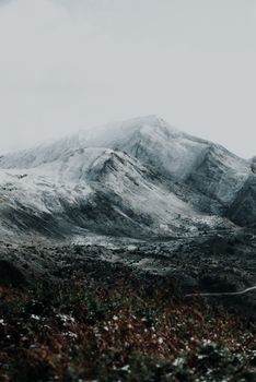 A breathtaking view of serene snow-capped mountains with a moody atmosphere, perfect for winter themes.