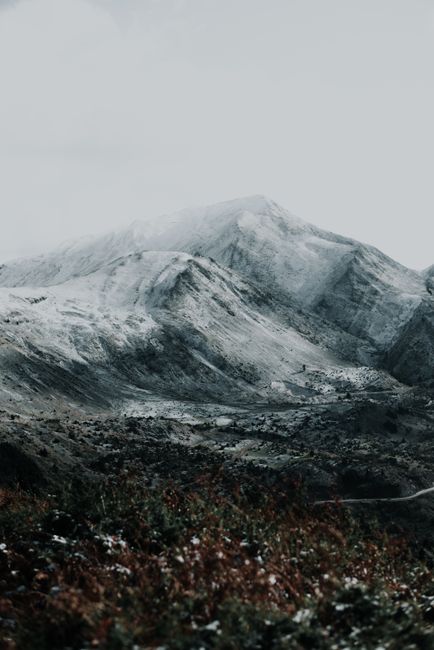 A breathtaking view of serene snow-capped mountains with a moody atmosphere, perfect for winter themes.