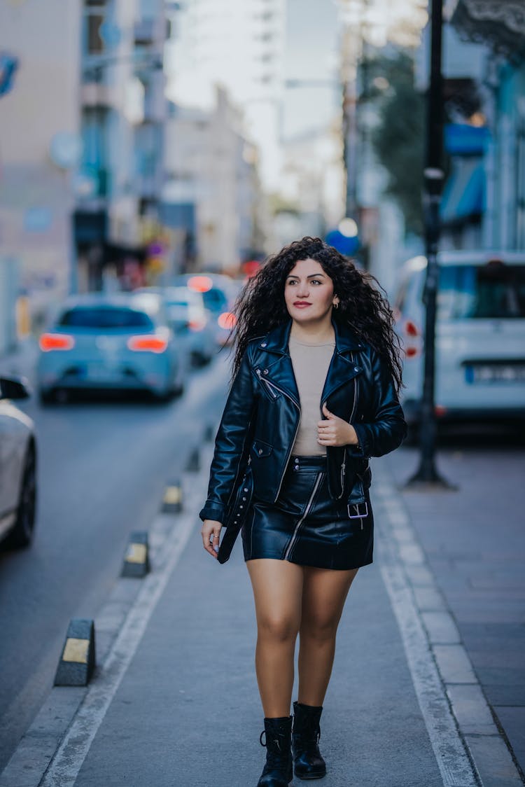 Young Woman In A Skirt And Leather Jacket Walking On The Street 