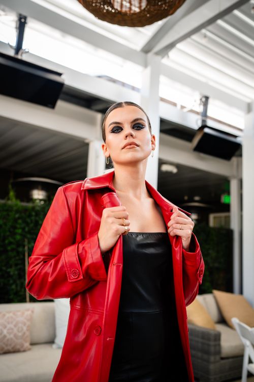 Free Fashionable young woman in a red coat posing indoors with a stylish expression. Stock Photo