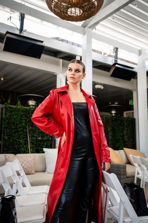 Free Confident woman in red coat and black outfit posing indoors, showcasing modern fashion. Stock Photo