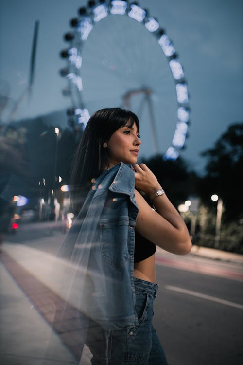 Woman Holding Denim Jacket in Front of a Ferris Wheel