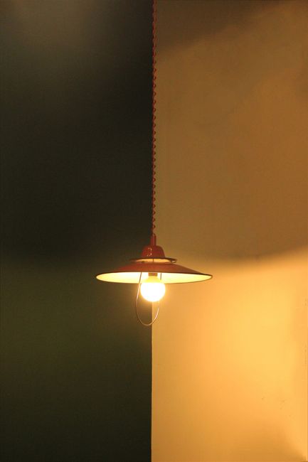 A solitary vintage lamp illuminates a room, casting warm light against a two-tone wall.