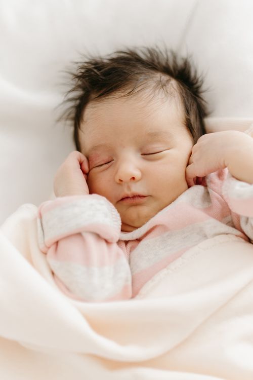 Free A serene newborn baby with brown hair sleeping wrapped in a soft blanket, embodying innocence and tranquility. Stock Photo