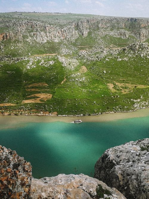 Free A serene cruise ship journeys along a picturesque river surrounded by rocky hills. Stock Photo