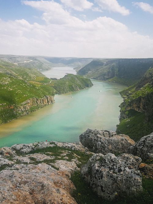 Free Breathtaking aerial view of a canyon landscape with a winding river and rugged cliffs under a bright sky. Stock Photo