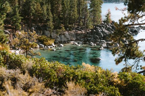 Free Captivating view of Lake Tahoe's emerald waters surrounded by lush forest and rocky shoreline. Stock Photo