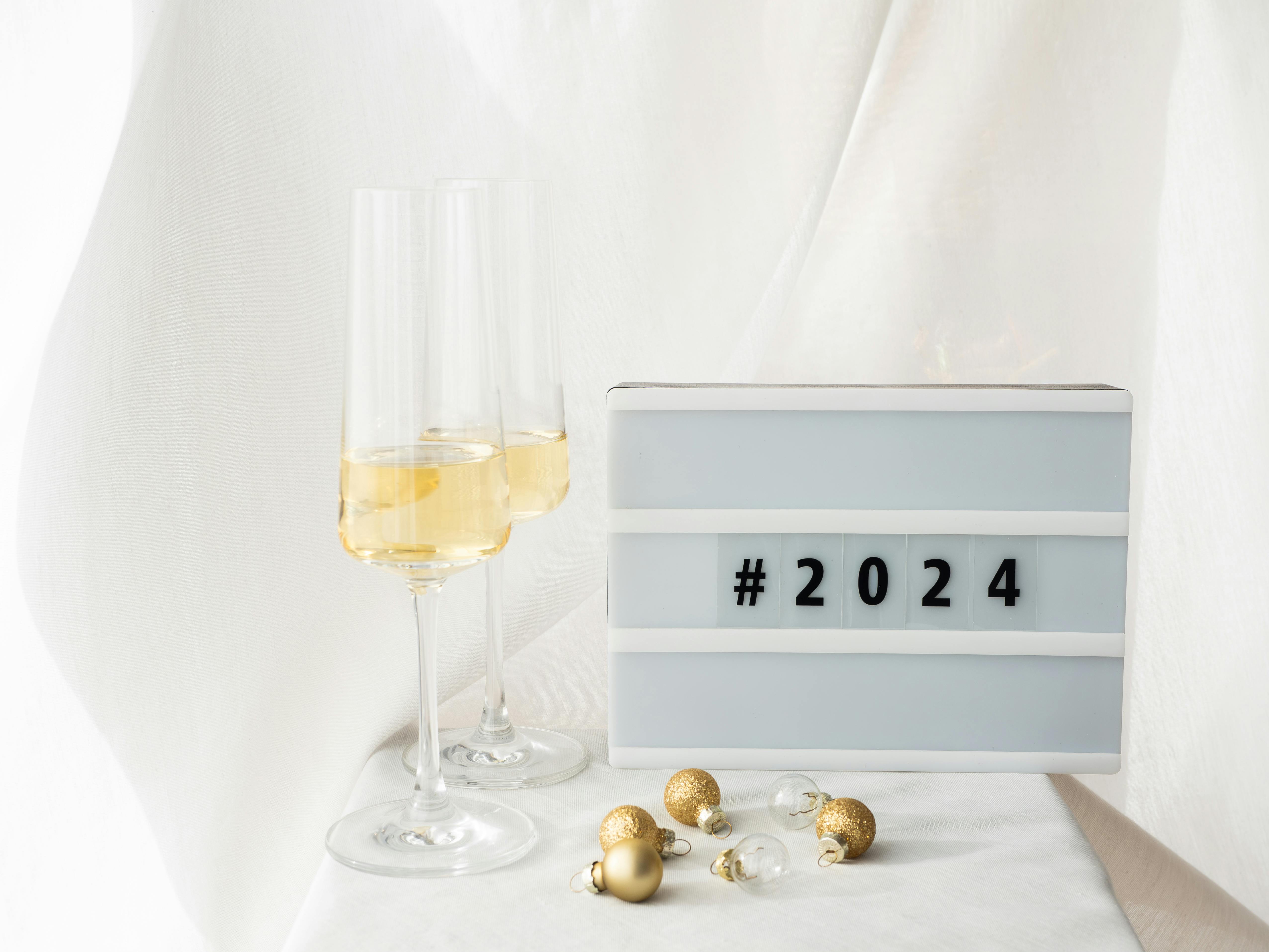 Festive Decorations With Champagne Glasses On A White Background And A   Free Photo Of Festive Decorations With Champagne Glasses On A White Background And A Lightbox With The Hashtag 2024 