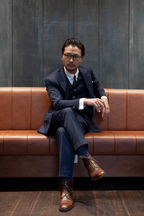 Man in a Suit and Eyeglasses Sitting on a Leather Sofa