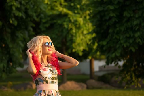 Free A stylish woman with colorful hair enjoys a sunny day in a park, capturing the joy of summer. Stock Photo