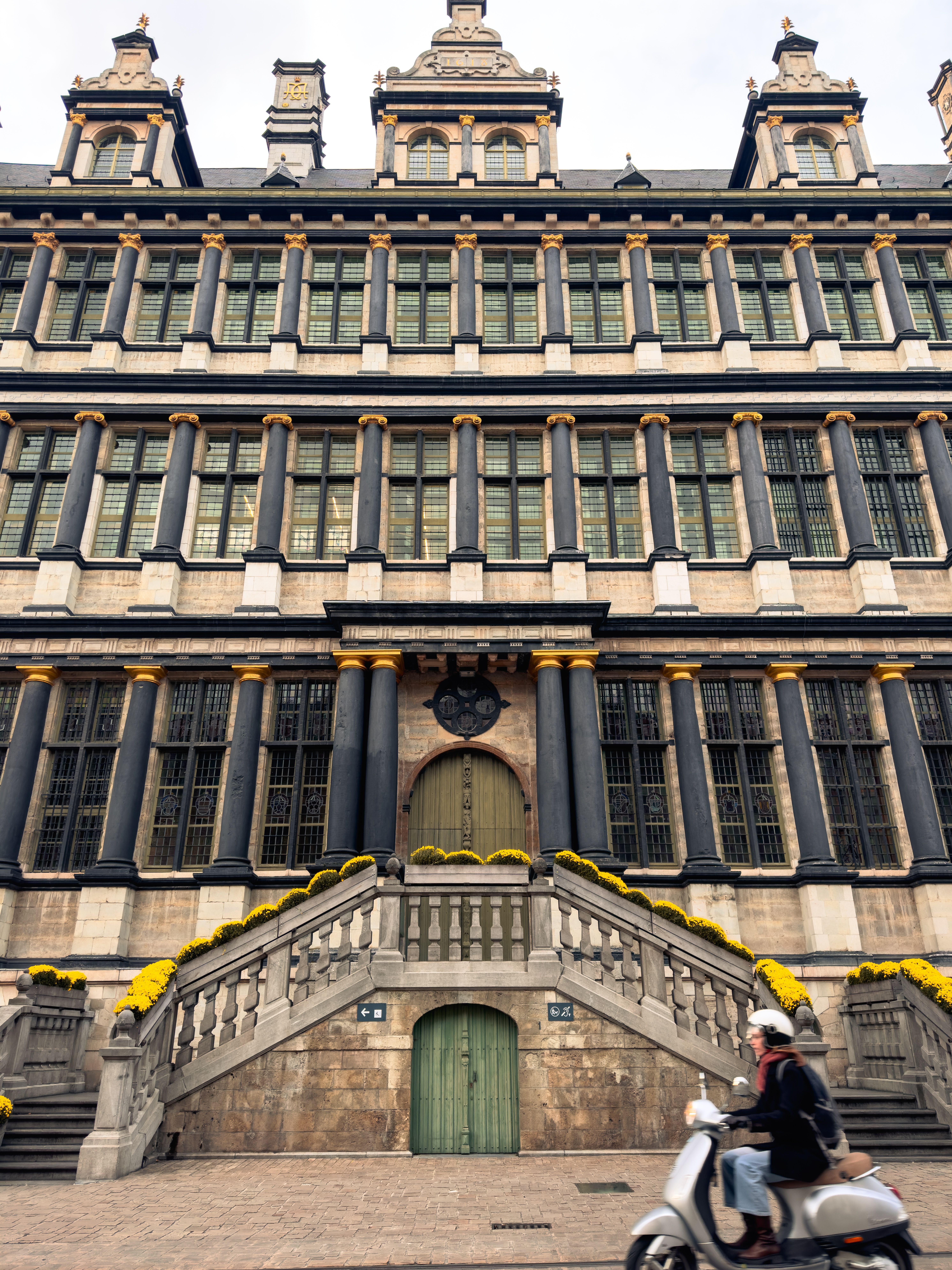 Stunning Renaissance architecture with symmetry in Gent, Belgium. A scooter passes by.