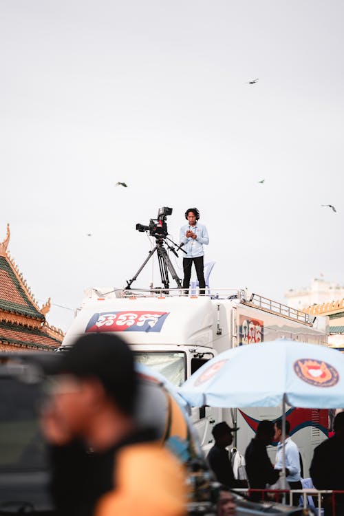 Man Standing with Camera on Truck Roof