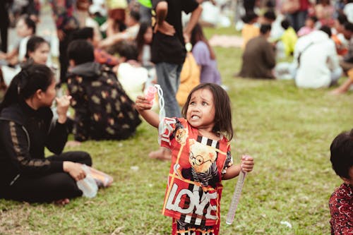 Girl Playing with a Toy in a Crowded Park
