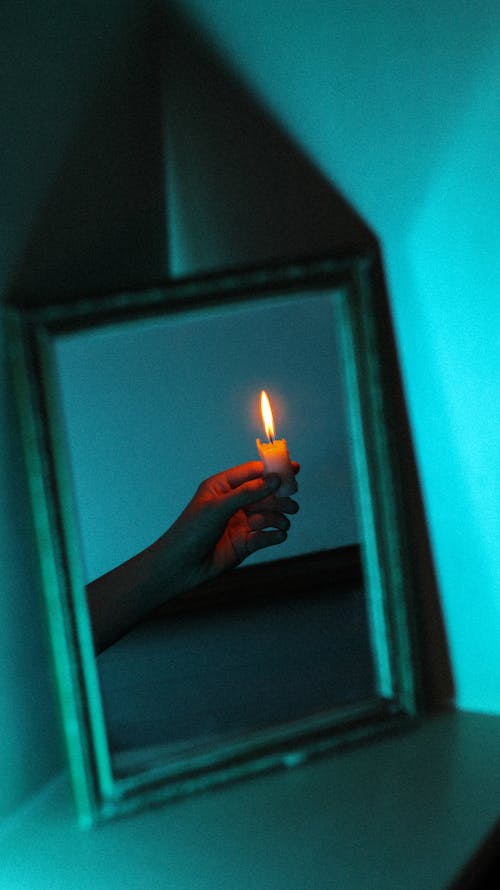 Abstract Image of a Hand Holding a Burning Candle in a Blue Interior