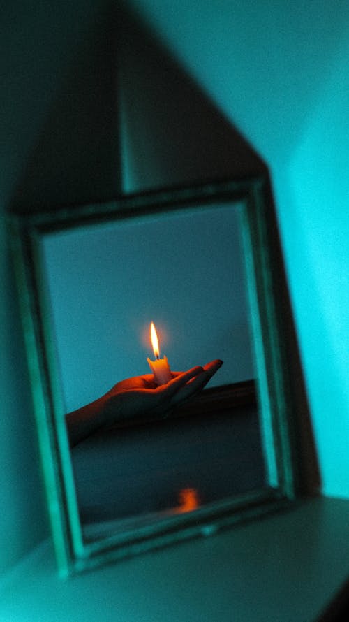 Reflection of a Hand Holding a Candle in the Mirror