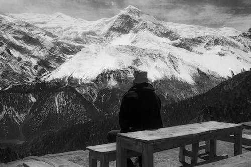 Free Black and White Photo of a Man Contemplating Mountains in Snow Stock Photo