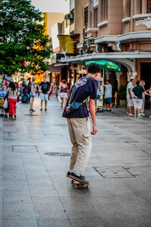 Young Man Riding a Skateboard on a Crowded City Walkway