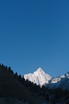 A stunning view of a snow-covered mountain peak against a clear blue sky, captured in winter.