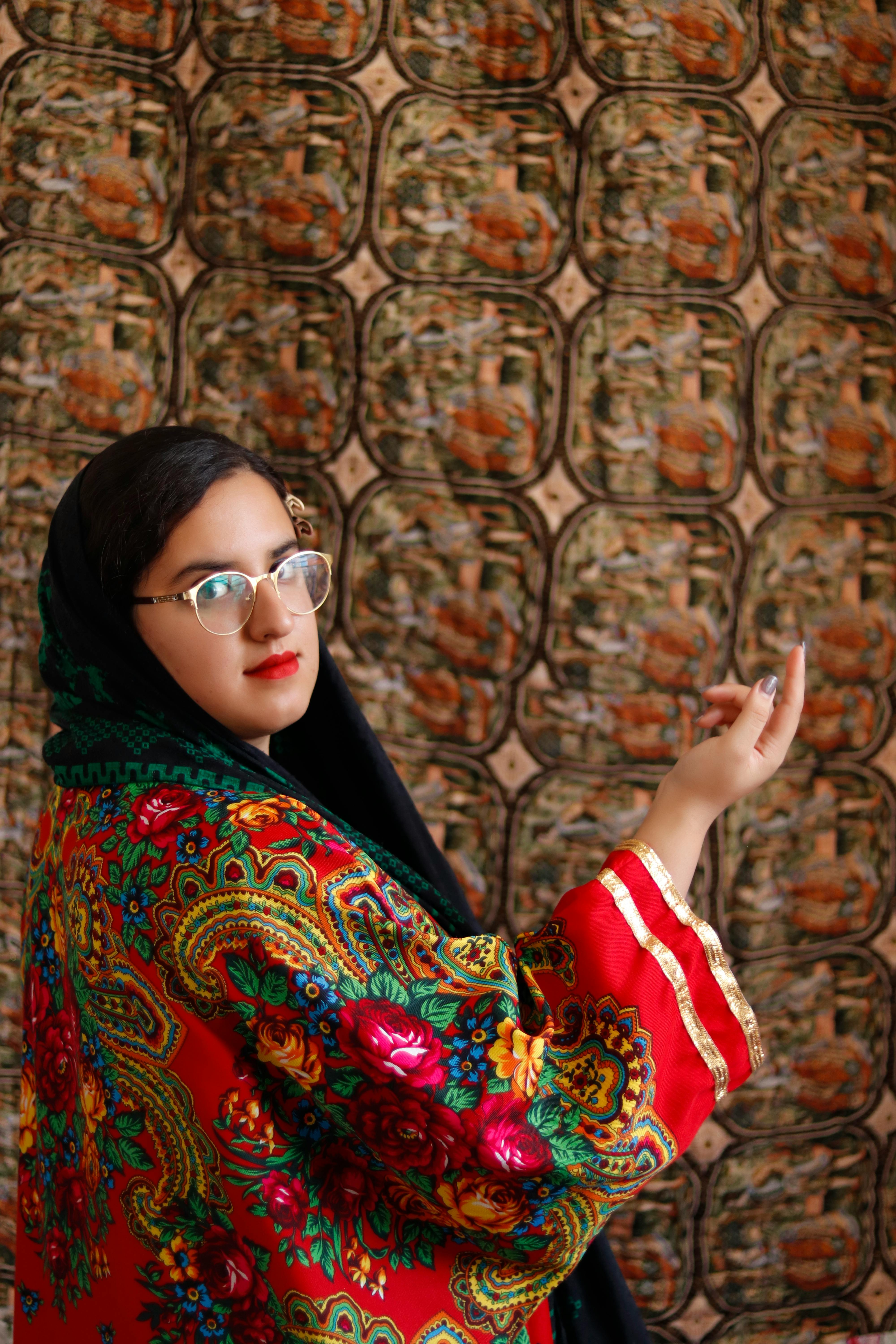 Woman in vibrant traditional folk attire with intricate patterns posing indoors.