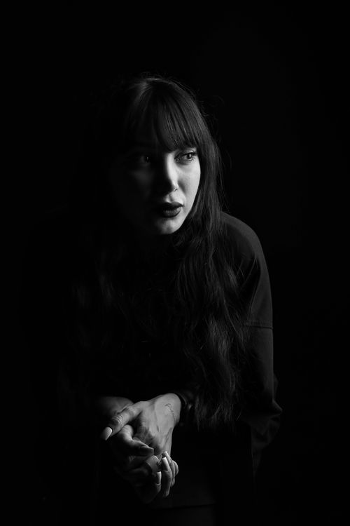 Free An evocative black and white portrait of a woman with bangs in a studio setting. Stock Photo