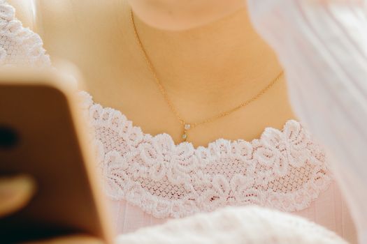 A close-up of a woman wearing a lace top and gold necklace, focusing on fashion and elegance.