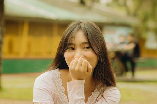 Young Woman Sitting Outside with Hand under Her Chin 