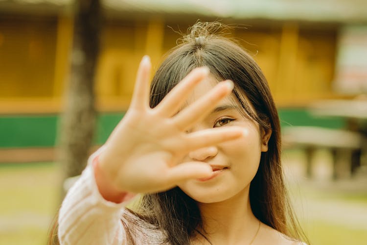 A Woman With Her Hand In Front Of Her Face 