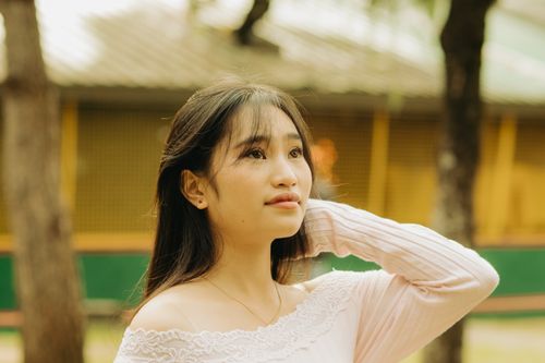 Free Beautiful young Asian woman gazing upward in a sunny park setting. Stock Photo