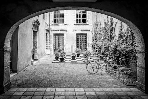 Black and White Photo of an Arch with a View of the Yard 