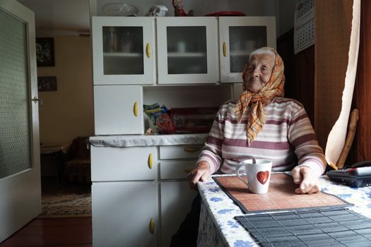 An elderly woman sitting at a table in a kitchen