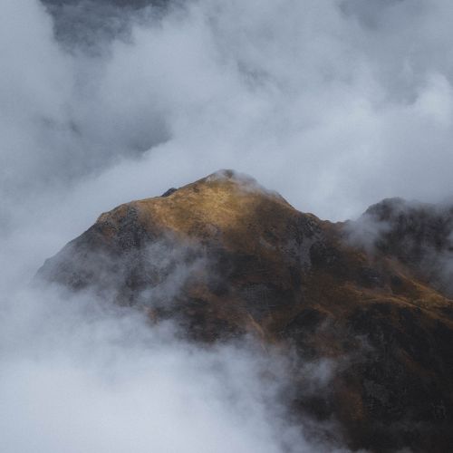 Free A stunning view of a solitary mountain peak enveloped by clouds, capturing nature's splendor. Stock Photo