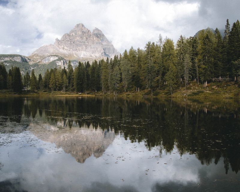 Pădure și munte reflectat în lac alpin în zona Dolomiți