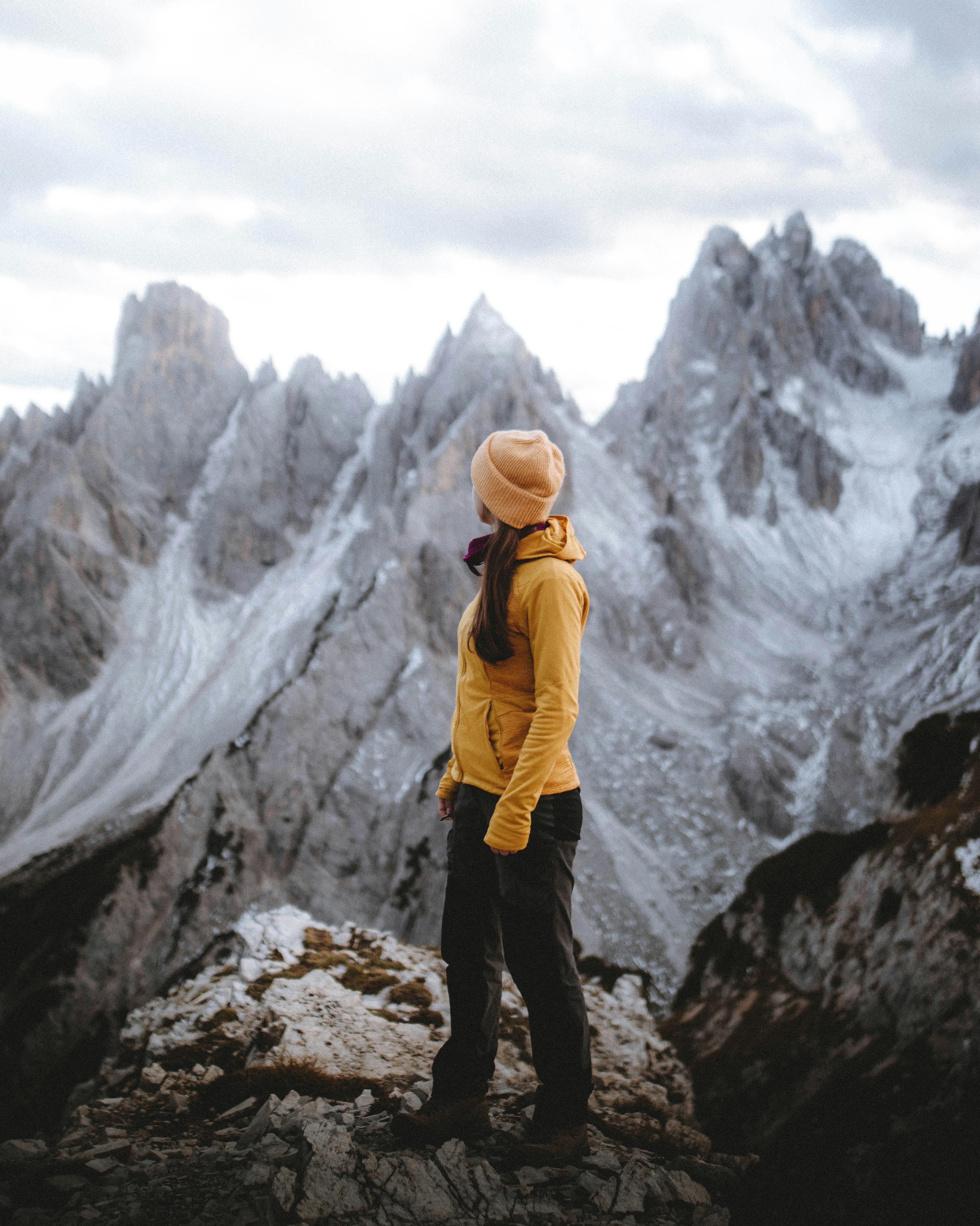 Hiker in warm clothing admires the snowy peaks of the Dolomites in winter.