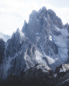 A breathtaking view of towering, snow-capped, rocky mountain peaks under a pale sky.