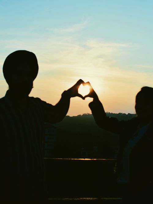 Free Silhouette of a couple forming a heart shape with hands at sunset in Chandigarh, India. Stock Photo