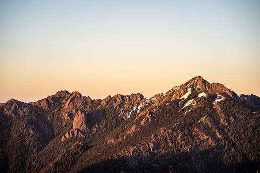 Stunning view of the Olympic Mountains at sunrise, showcasing rocky peaks and snow patches.